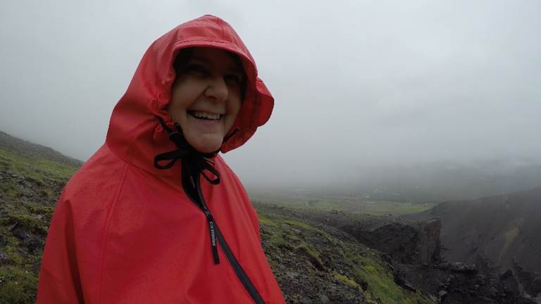 A person wearing a red hat and shirt with a mountain in the background