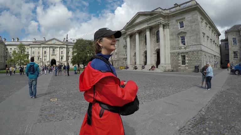 A person standing in front of a building. Description generated with very high confidence