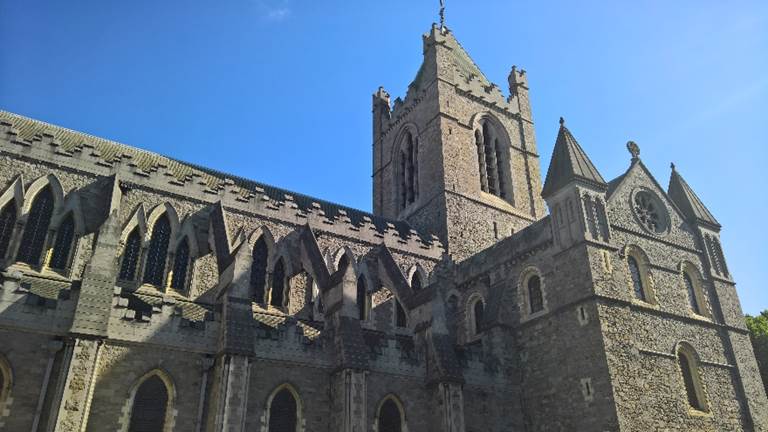 A large stone building with a clock tower. Description generated with very high confidence