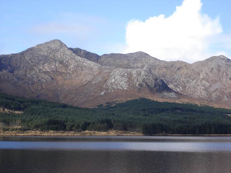 A body of water with a mountain in the background. Description generated with very high confidence