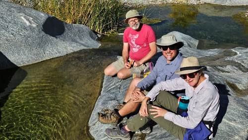 A group of people sitting on a rock by water